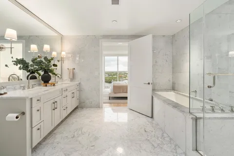 a bathroom with a double vanity sink and mirror with bathtub