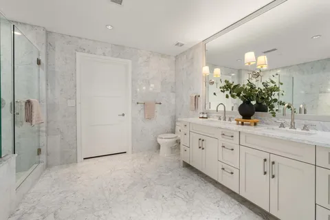 a spacious bathroom with a double vanity sink toilet mirror and shower