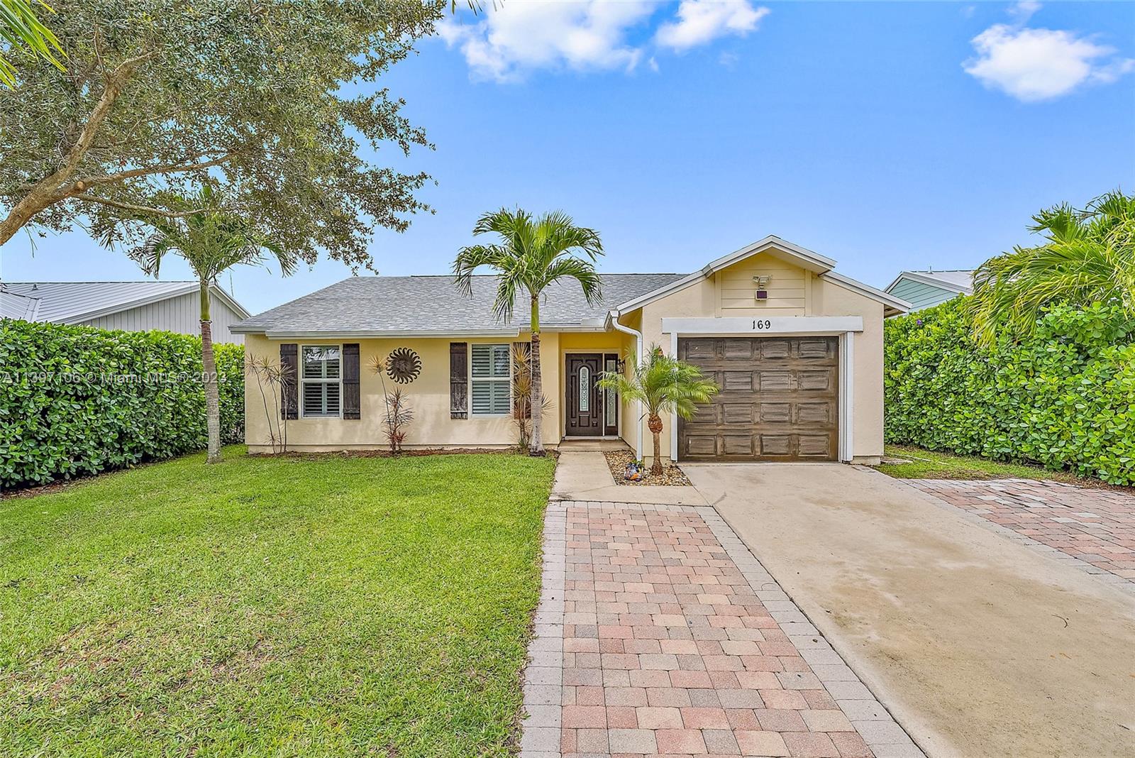 169 Greentree Circle Jupiter, FL 33458 - Photo 1 of 38 a front view of a house with a garden and yard