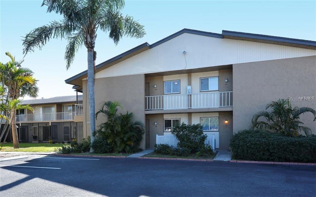 2938 Clark Road, Unit 204 Sarasota, FL 34231 - Photo 1 of 1 a front view of a house with a yard and potted plants