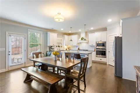 a kitchen with a table chairs a sink dishwasher stove and cabinets with wooden floor