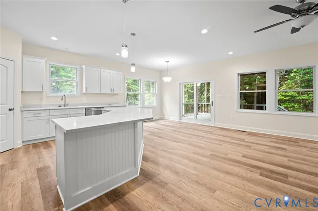 a large kitchen with stainless steel appliances granite countertop a sink stove and a large window with wooden floor