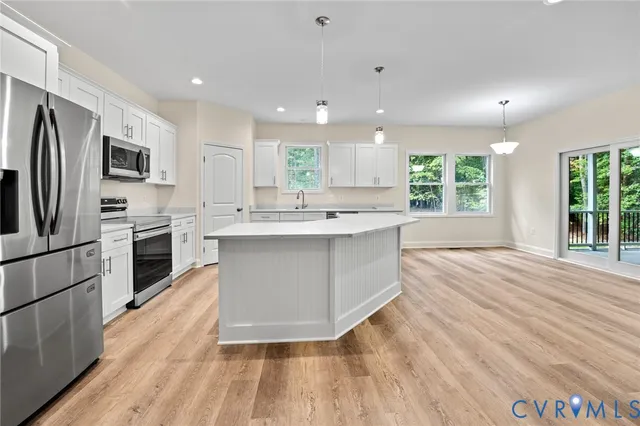 a large kitchen with kitchen island a large counter top space stainless steel appliances and cabinets