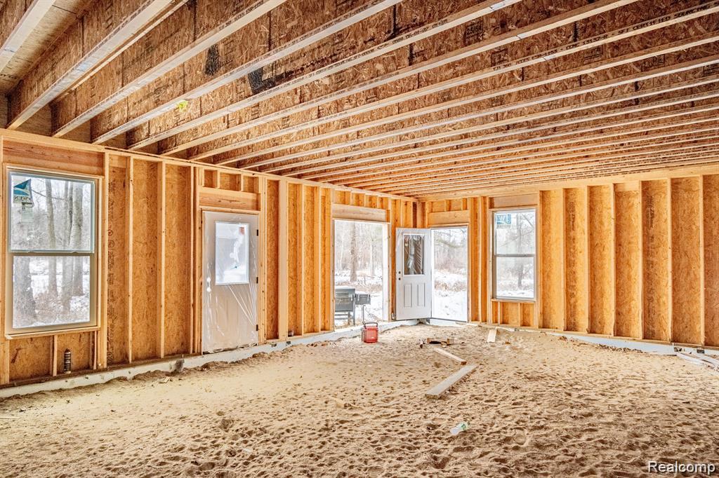 1601 West Rose Center Road Holly, MI 48442 - Photo 7 of 14 Framed interior structure with exposed ceiling joists, multiple windows, and two exterior doors
