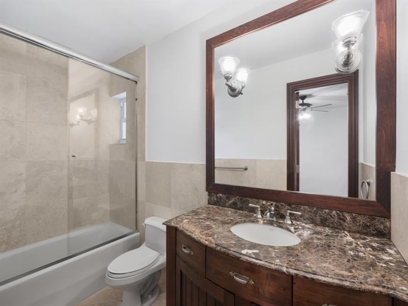 441 Ridge Road Coral Gables, FL 33143 - Photo 21 of 23 a bathroom with a granite countertop sink toilet mirror and shower