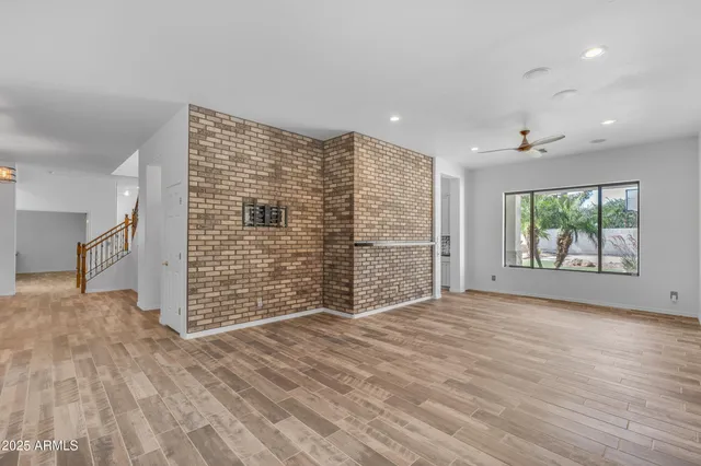 a view of an empty room with a window and wooden floor