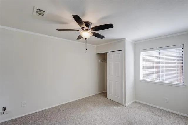 an empty room with closet and a ceiling fan