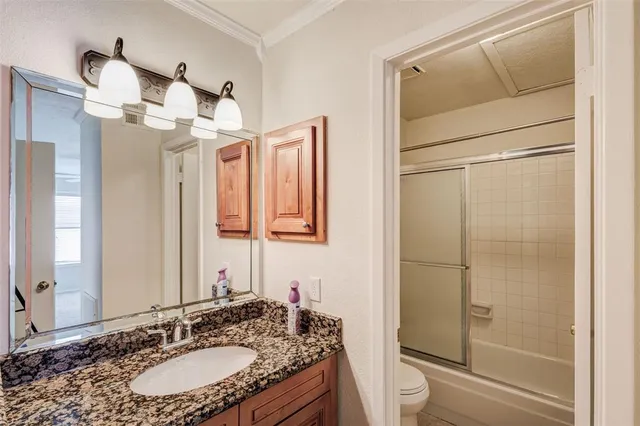 a bathroom with a granite countertop sink a toilet a mirror and shower