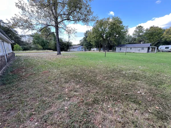 a view of a house with yard and trees in the background