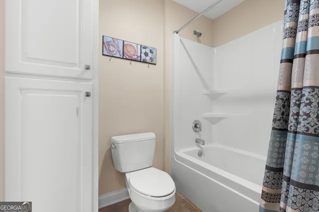 a spacious bathroom with double sink a toilet a shower and a large mirror
