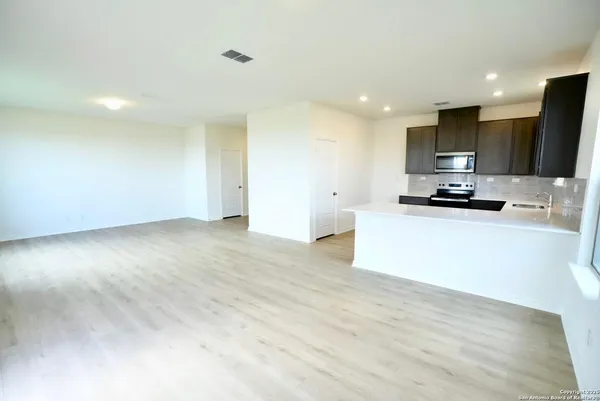a view of kitchen with kitchen island a sink wooden floor and a stove