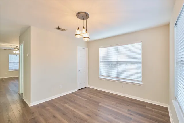 a view of an empty room with a window and wooden floor