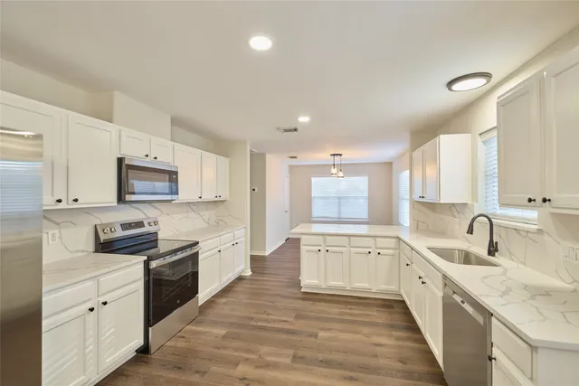 a large kitchen with stainless steel appliances granite countertop a lot of counter space and wooden floors