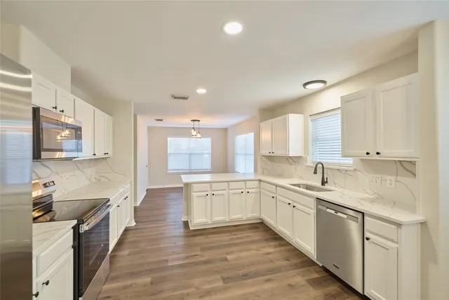 a large kitchen with stainless steel appliances granite countertop a lot of counter space and wooden floors