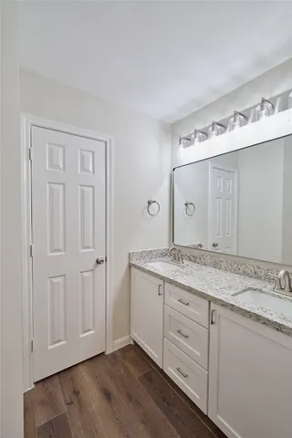 a bathroom with a granite countertop double vanity sink and mirror