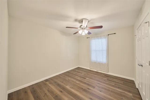 a view of a room with wooden floor and a ceiling fan
