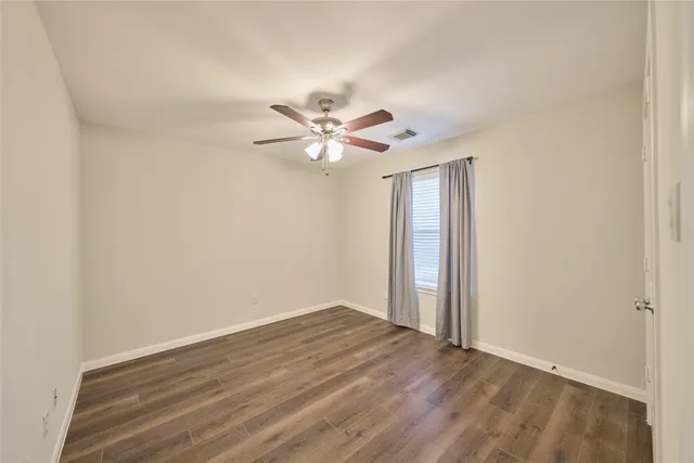 an empty room with wooden floor and ceiling fan