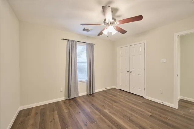 an empty room with wooden floor closet and fan chandelier fan