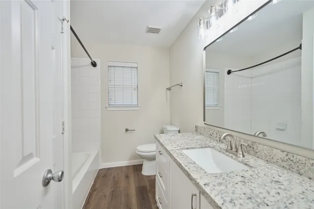 a bathroom with a granite countertop sink a mirror and a toilet
