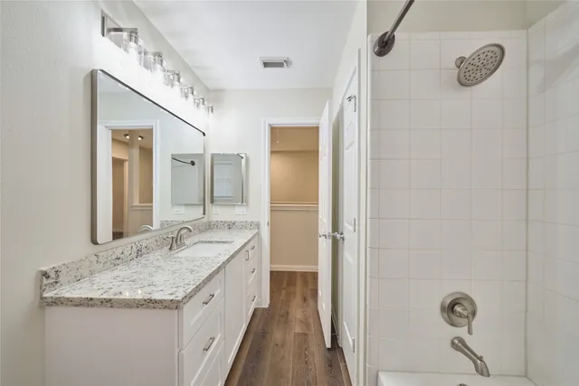 a bathroom with a granite countertop sink a mirror and a shower