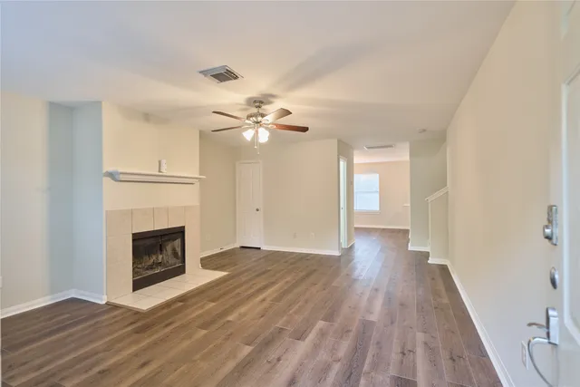 a view of an empty room with wooden floor and fireplace