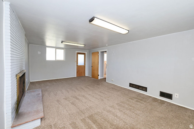 1272 Cook Street Ogden, UT 84404 - Photo 30 of 58 Carpeted room featuring a white brick fireplace with a stone hearth, two windows, and two natural wood doors