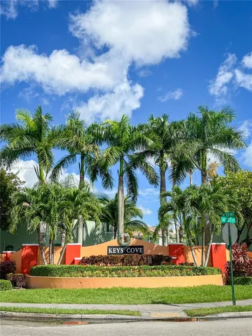 a front view of multi story residential apartment building with yard and sign