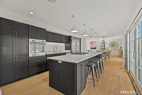 a kitchen with stainless steel appliances kitchen island granite countertop a table chairs and a refrigerator