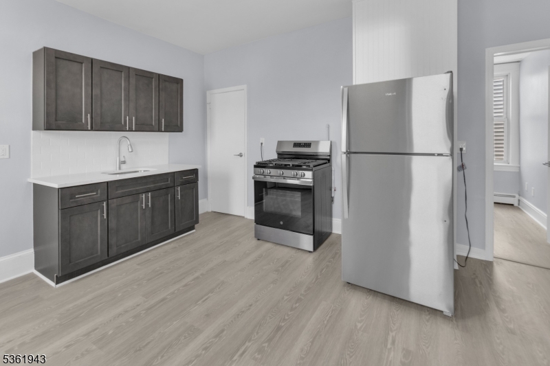 215 Delaware Street, Unit 6 Elizabeth Port, NJ 07206 - Photo 1 of 11 a kitchen with stainless steel appliances granite countertop a refrigerator stove a sink and dishwasher with wooden floor