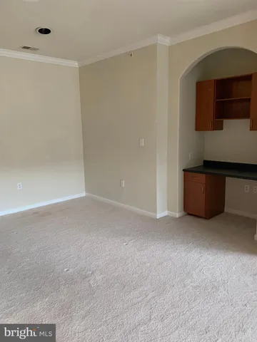 a view of an empty room with kitchen cabinet and a window