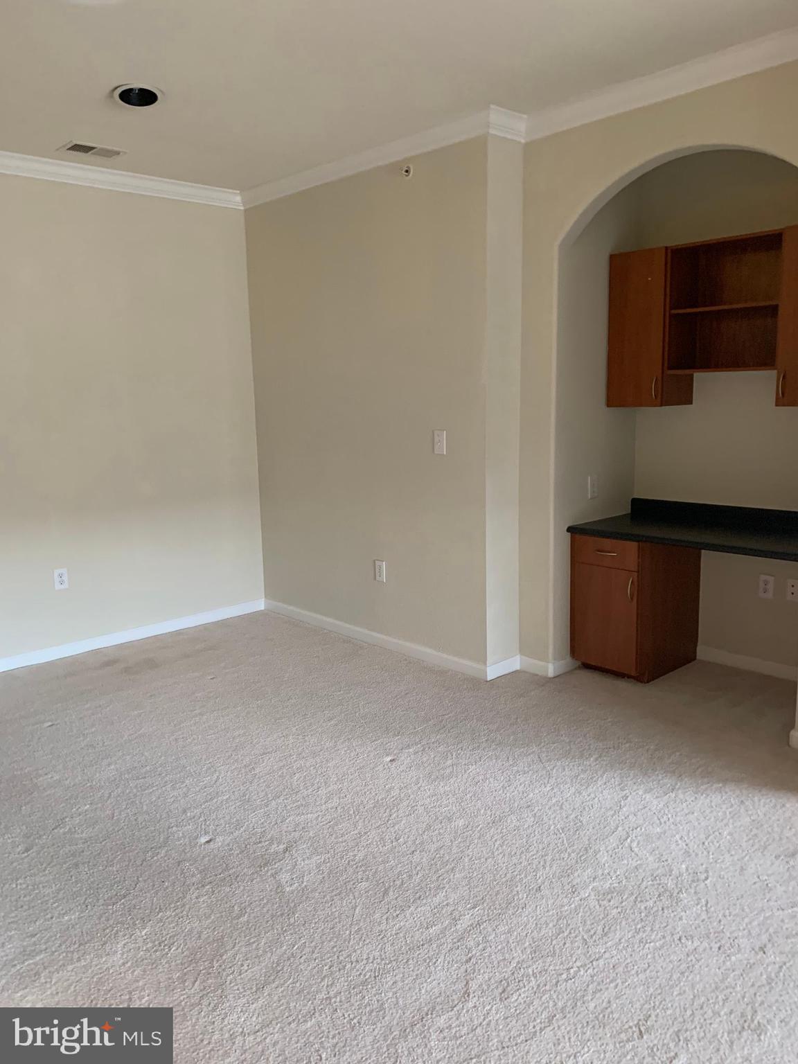 13501 Kildare Hills Terrace, Unit 402 Germantown, MD 20874 - Photo 4 of 14 a view of an empty room with kitchen cabinet and a window