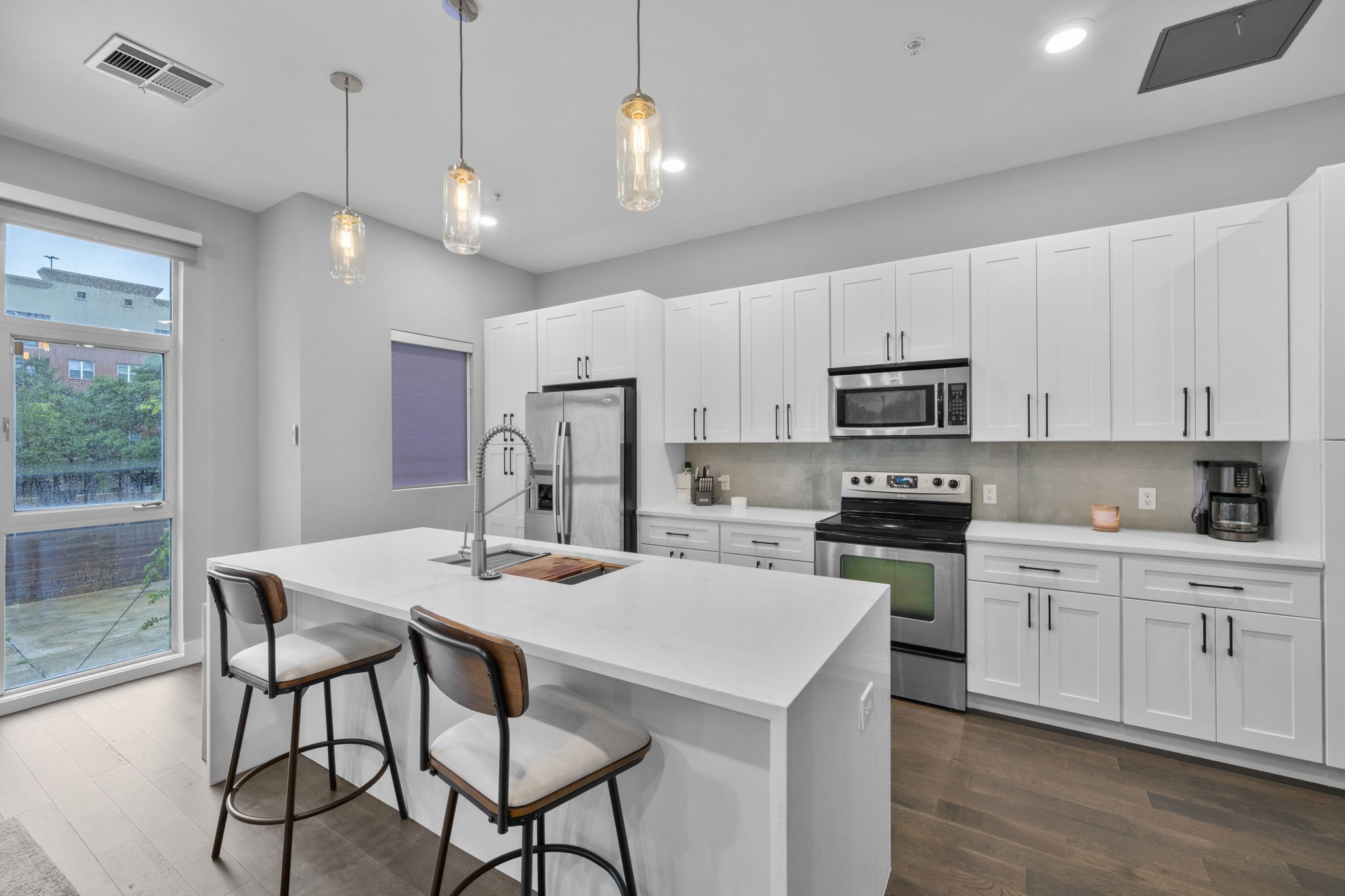 207 Pierce Street, Unit 209 Houston, TX 77002 - Photo 4 of 13 a kitchen with stainless steel appliances kitchen island granite countertop a dining table chairs refrigerator and microwave