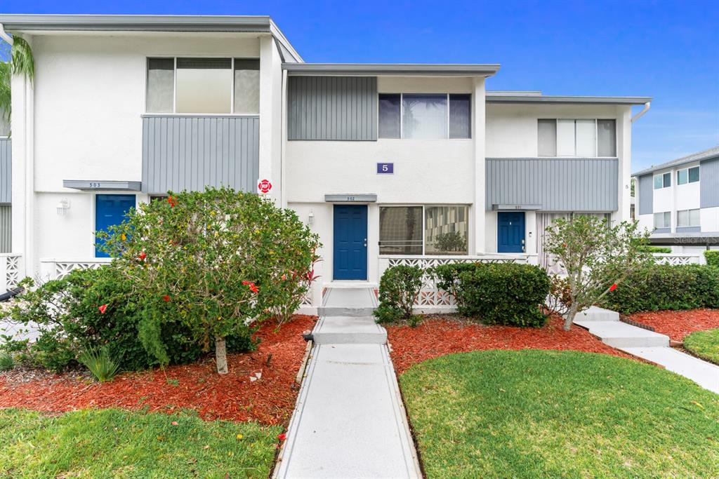14800 Walsingham Road, Unit 502 Largo, FL 33774 - Photo 1 of 1 a front view of a house with a yard and potted plants