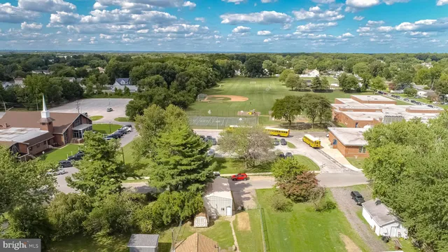 an aerial view of a residential houses with outdoor space and trees all around