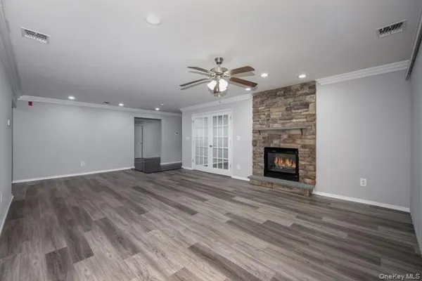 a view of an empty room with wooden floor a fireplace and a window