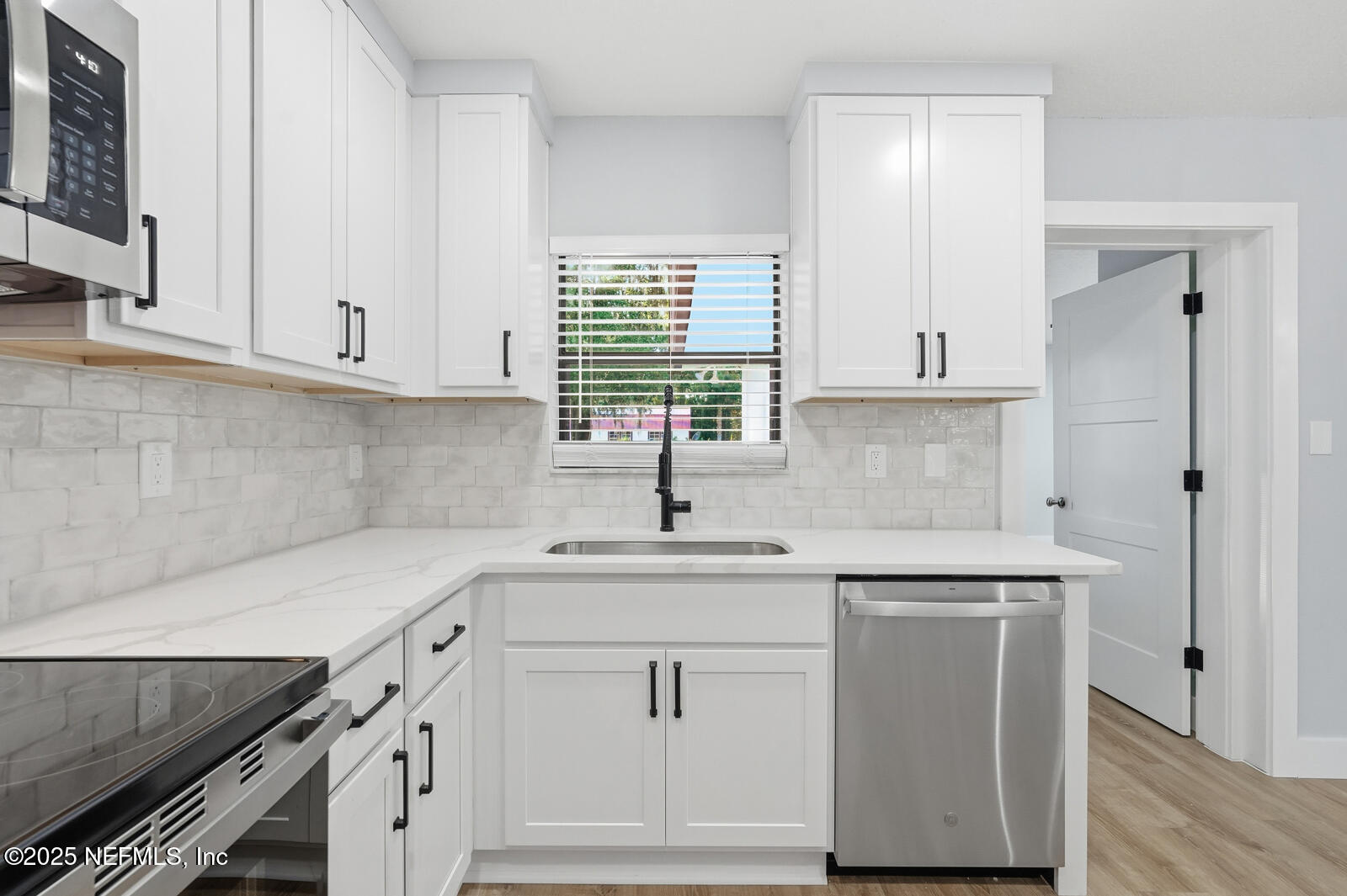 341 Alabama Avenue Palatka, FL 32177 - Photo 17 of 47 a kitchen with white cabinets appliances a sink and a window