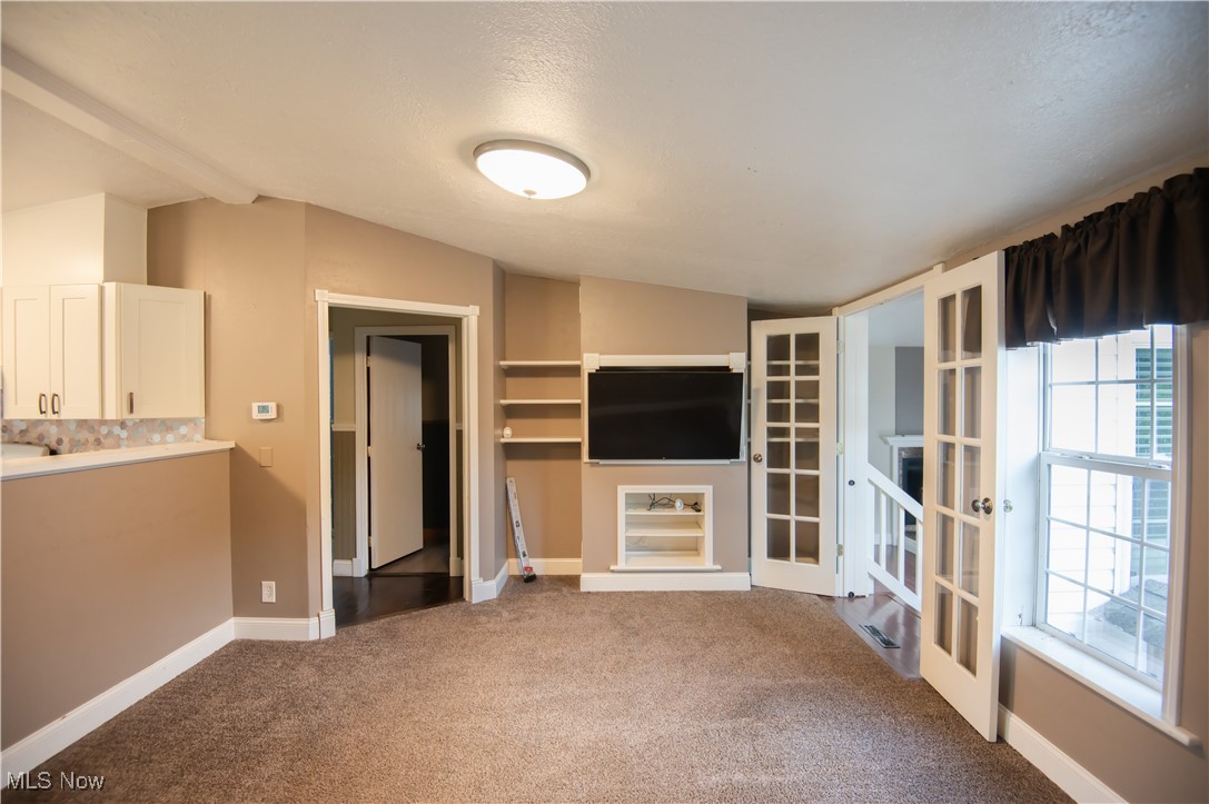 4594 Center Road Andover, OH 44003 - Photo 8 of 39 Unfurnished living room with light carpet, french doors, and a textured ceiling