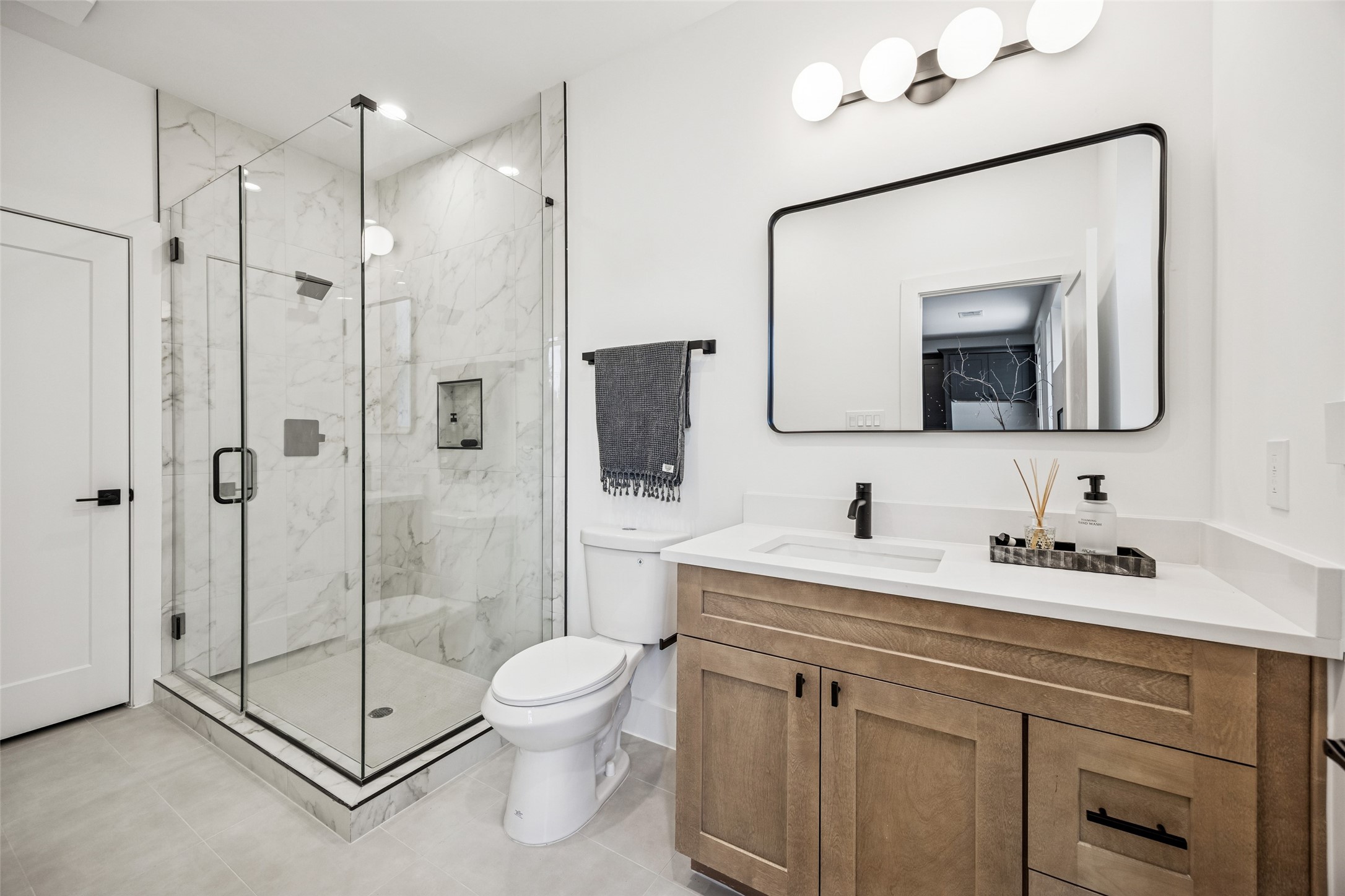 3008 Lamar Street Houston, TX 77003 - Photo 12 of 33 a bathroom with a toilet a sink a glass door a shower a mirror and vanity
