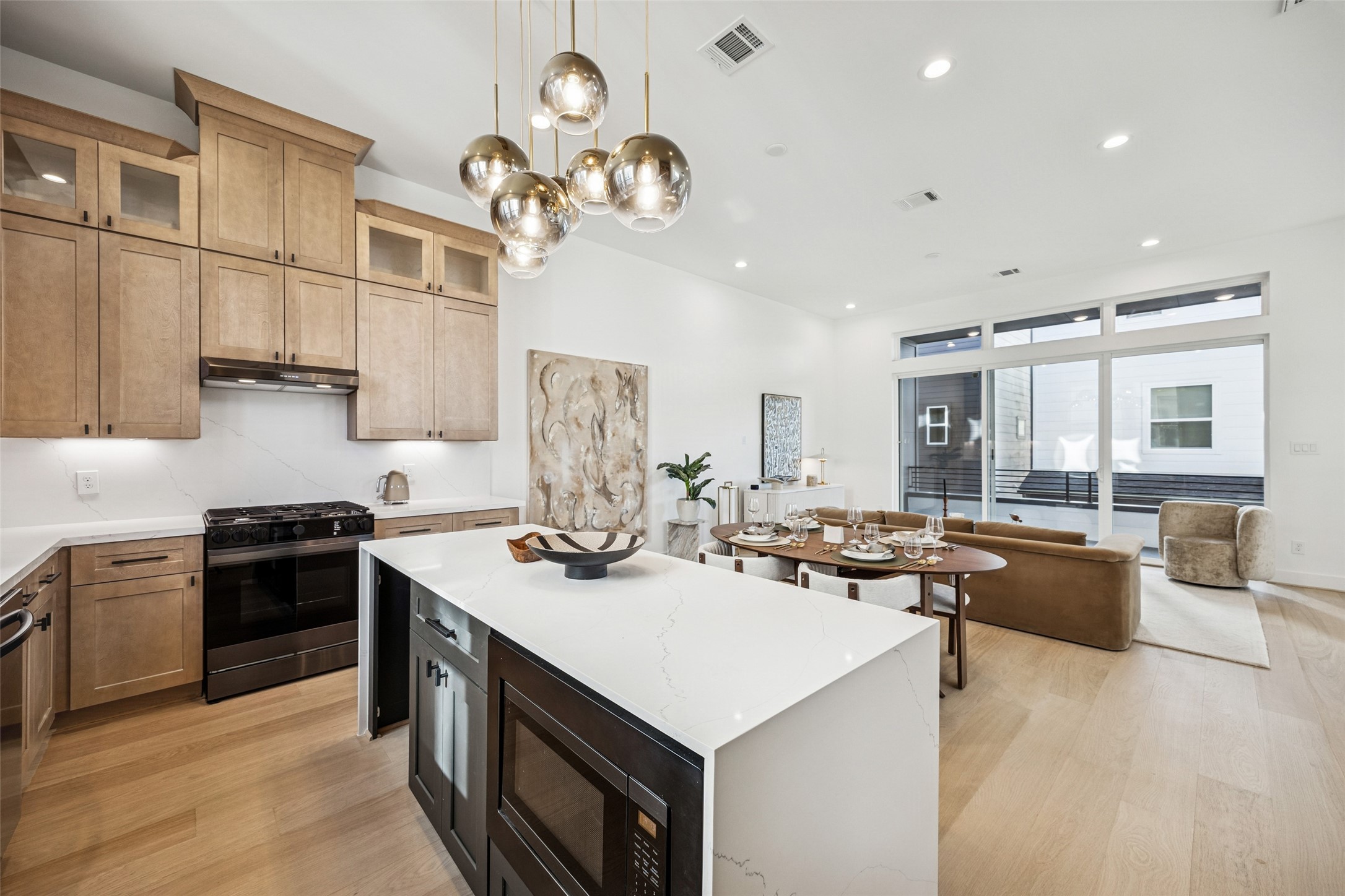 3008 Lamar Street Houston, TX 77003 - Photo 23 of 33 a kitchen with a stove a kitchen island a sink dishwasher a dining table and chairs with wooden floor