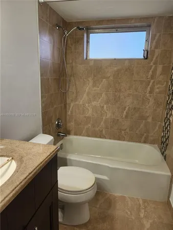 a bathroom with a granite countertop bathtub shower sink vanity and toilet