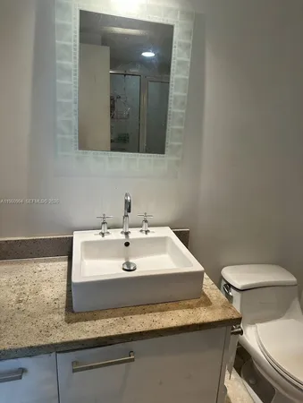 a bathroom with a granite countertop sink and a mirror