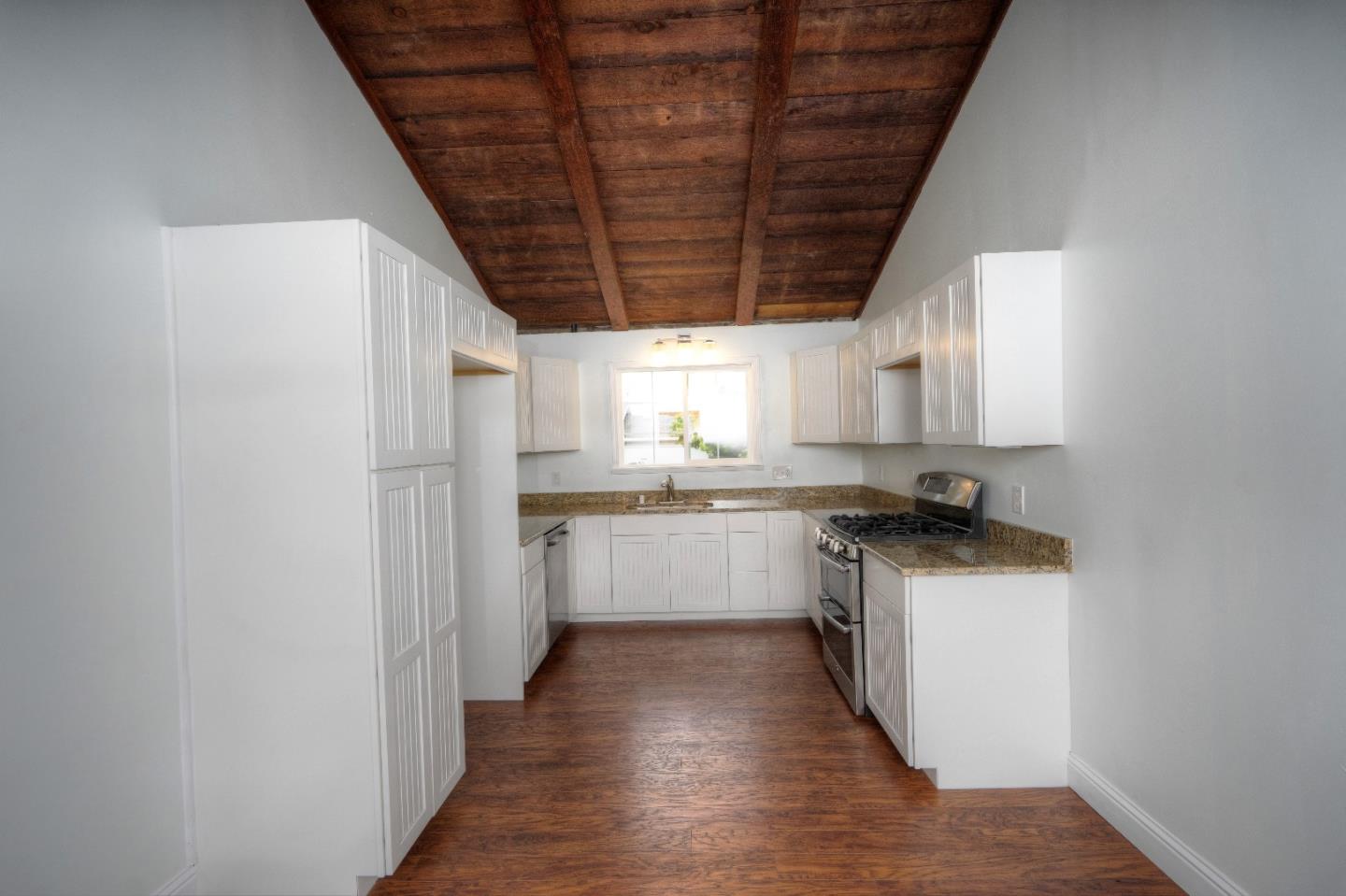 197 Ramona Avenue Pacifica, CA 94044 - Photo 9 of 26 a kitchen with granite countertop a refrigerator a sink dishwasher a stove and white cabinets with wooden floor