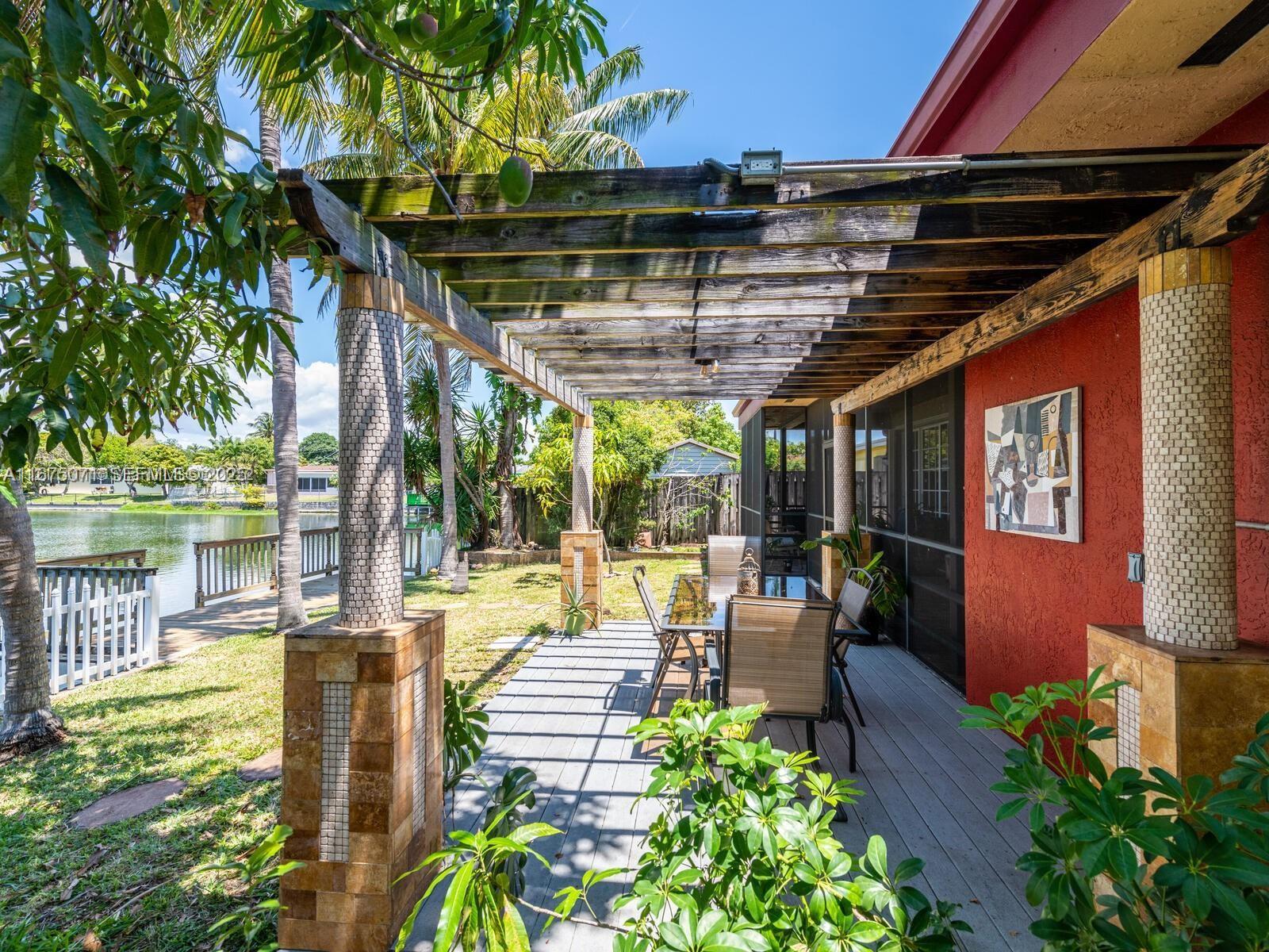 232 Southwest 7th Avenue Hallandale Beach, FL 33009 - Photo 21 of 48 a view of a patio with table and chairs potted plants with floor to ceiling window and wooden fence
