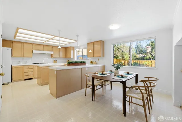 a kitchen with a table chairs a sink dishwasher window and cabinets