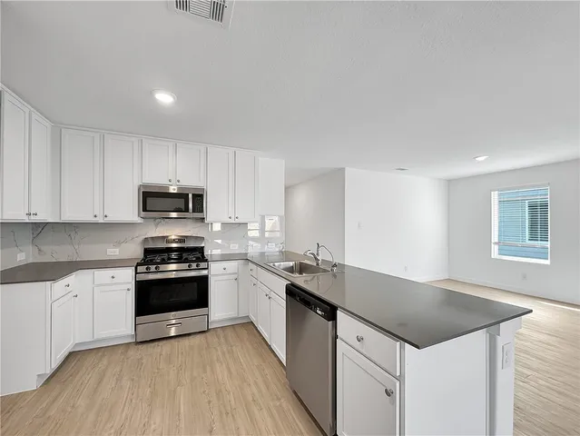 a kitchen with granite countertop white cabinets sink and stainless steel appliances