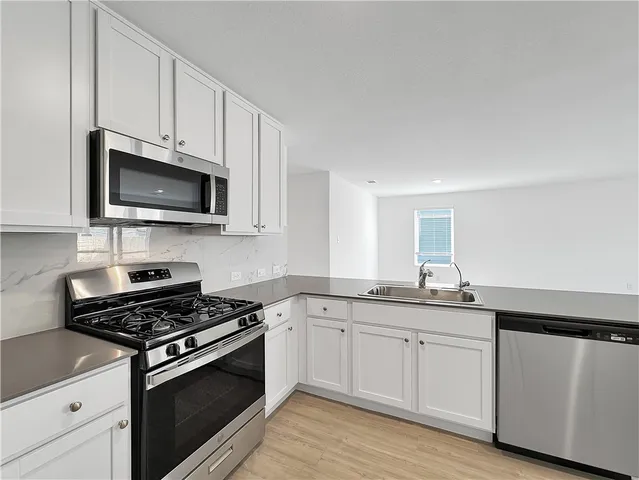 a kitchen with cabinets stainless steel appliances a sink and wooden floor