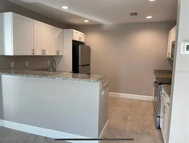 a kitchen with granite countertop a stove top oven microwave and cabinets