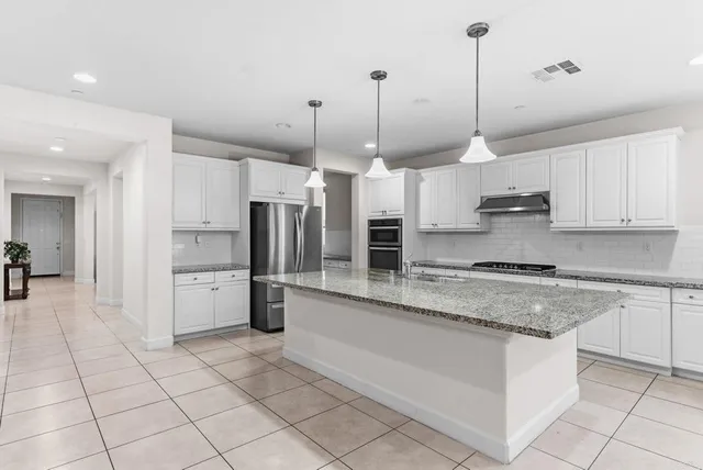 a kitchen with stainless steel appliances granite countertop a stove a sink and a refrigerator