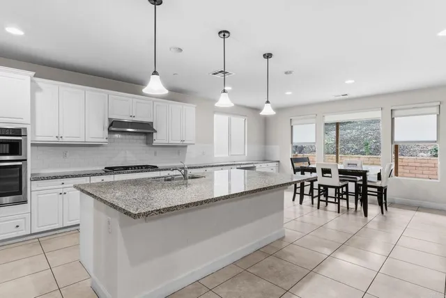 a large kitchen with kitchen island a dining table chairs and white cabinets