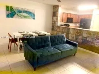 a living room with stainless steel appliances kitchen island granite countertop a sink and a black cabinets